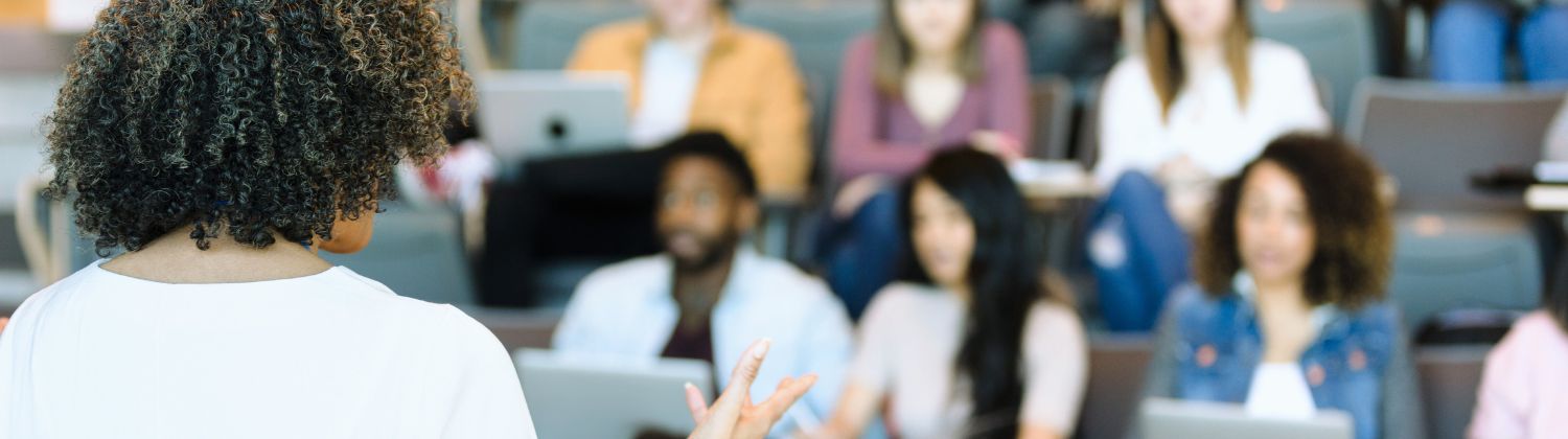 Professeure enseignant à un groupe d’étudiantes et d’étudiants dans une salle de classe universitaire, illustrant l’importance du financement des universités au Québec.